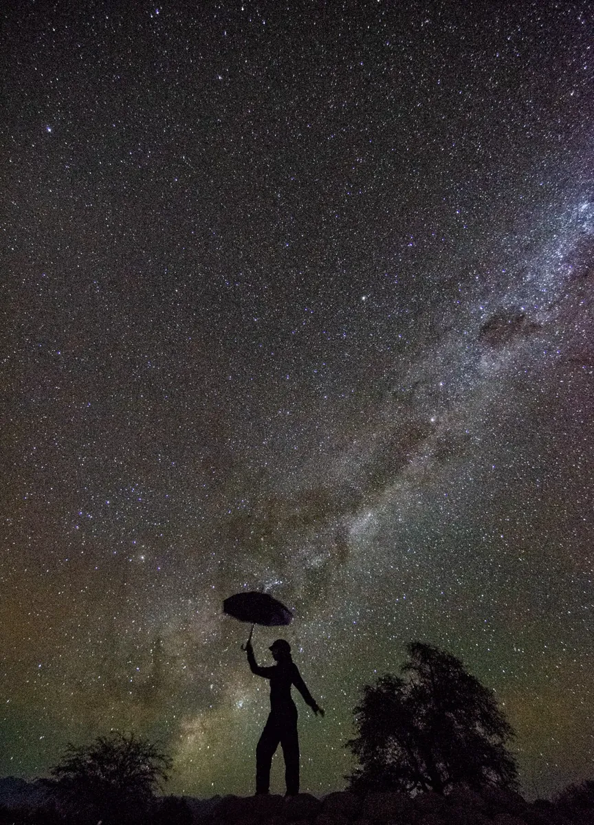 Silueta artística de mujer con paraguas bajo el cielo estrellado de Atacama