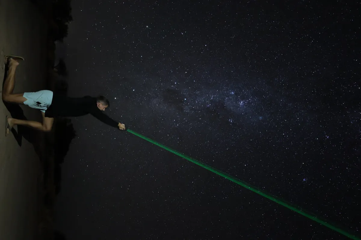 Hombre de rodillas señalando el cielo con puntero láser verde durante la charla