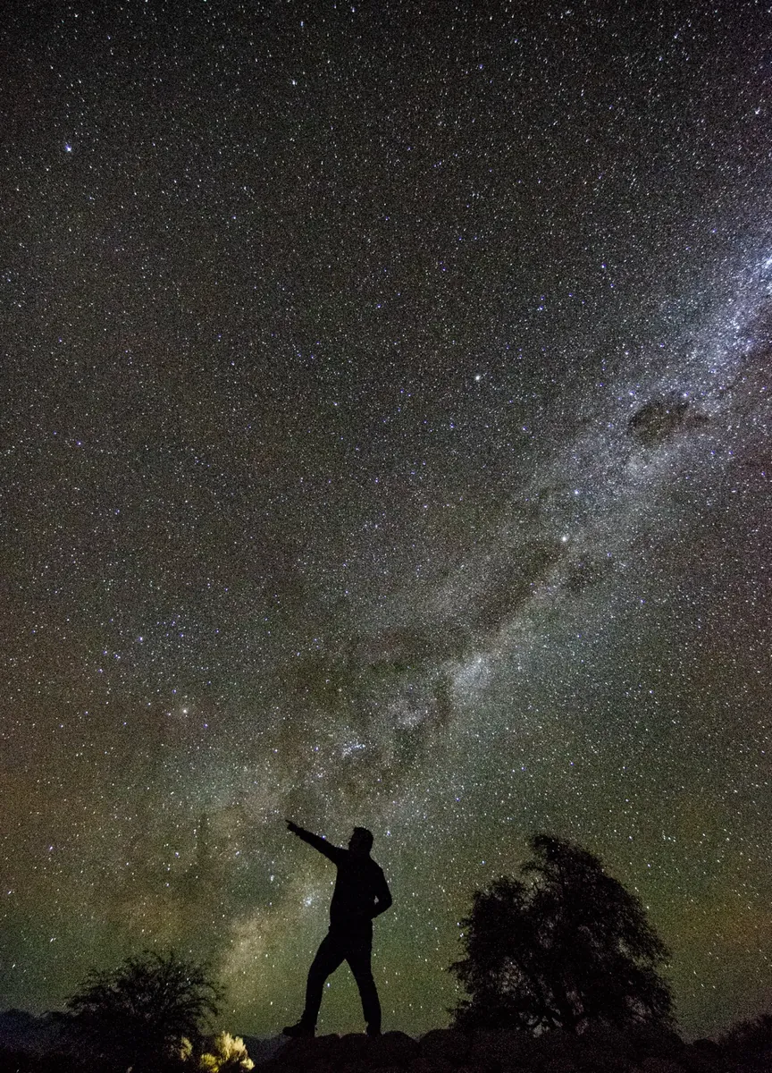 Silueta de hombre señalando la Vía Láctea espectacular en el cielo de Atacama